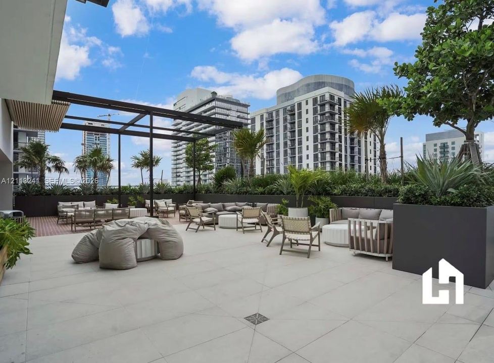 Expansive rooftop terrace featuring large-format stone pavers, a custom metal pergola, built-in perimeter planters, and integrated landscaping