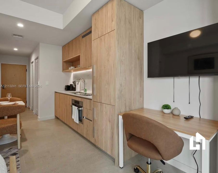 Kitchenette featuring wood-finish cabinetry, under-cabinet lighting, integrated appliances, and a matching built-in workstation