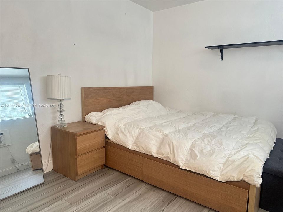 Neutral-toned wood-finish flooring and a black wall-mounted shelf