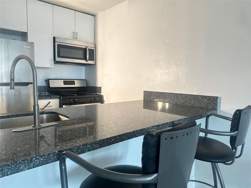 Kitchen featuring solid surface countertops, stainless steel appliances, built-in microwave, upper cabinetry, and a high-arc kitchen faucet