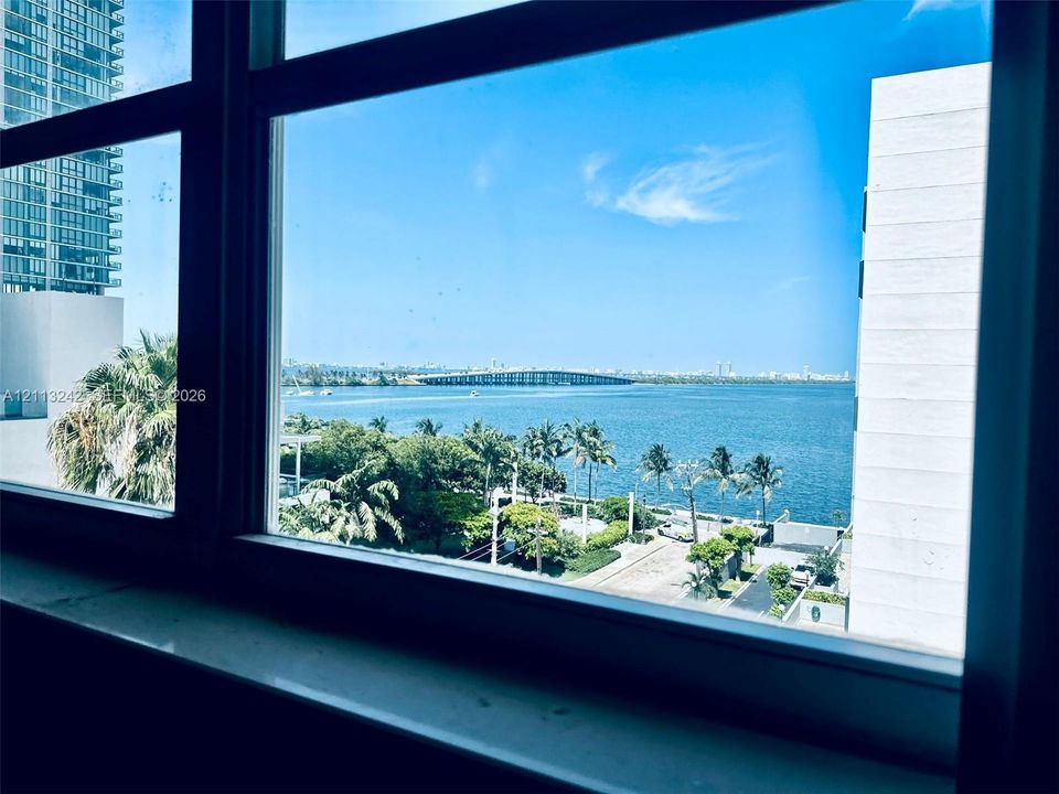 Large-pane window featuring a stone sill, showcasing expansive water, bridge, and coastal horizon imagery
