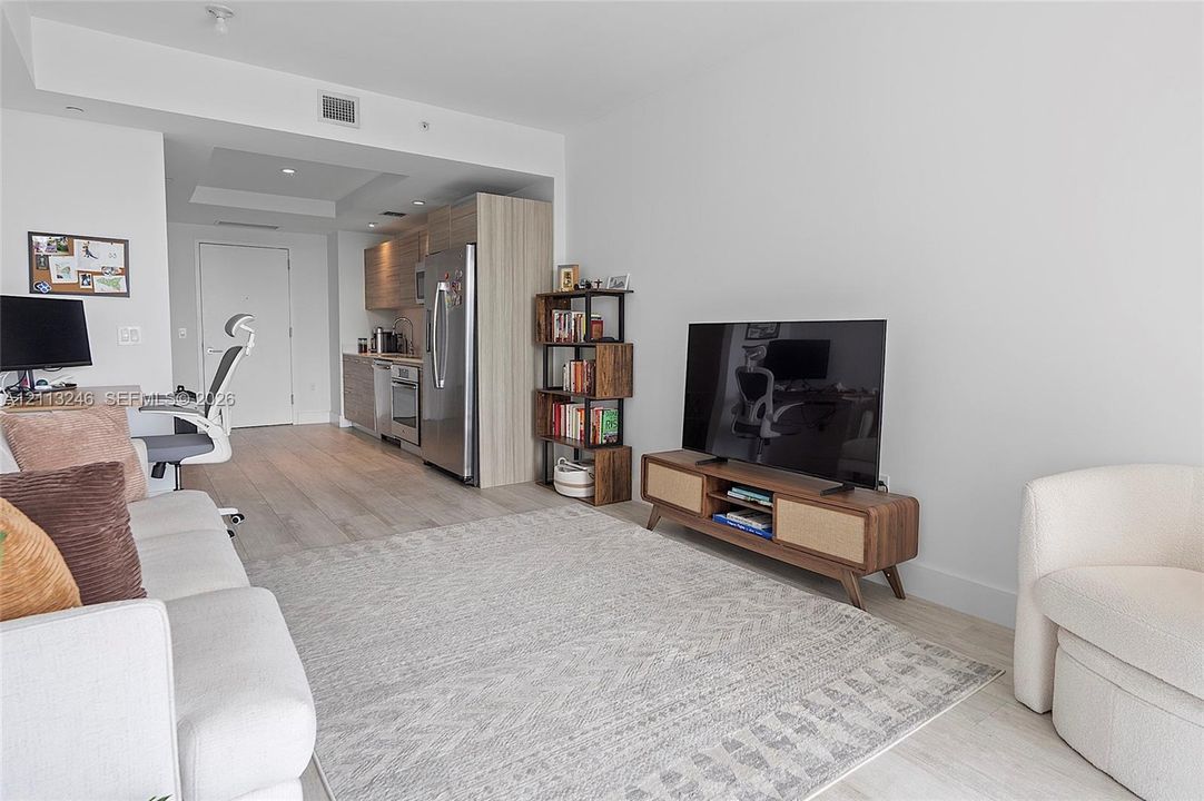Open-concept living space featuring wood-finish flooring, recessed lighting, and a kitchen equipped with stainless steel appliances and wood-grain cabinetry