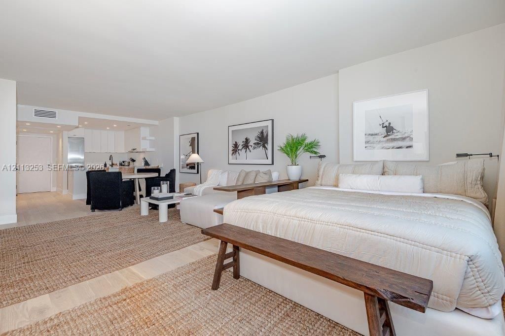 Open-concept interior featuring light-toned flooring, recessed ceiling lighting, and a kitchen area with white cabinetry and stainless steel appliances