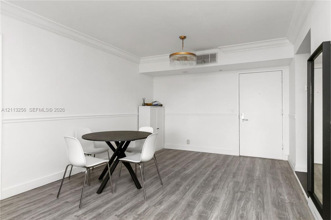Wood-finish flooring, crown molding, chair rail trim, and a gold-tone drum chandelier