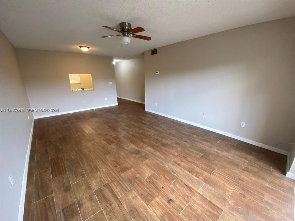 Wood-finish flooring, neutral wall tones, and ceiling fan with integrated lighting fixture