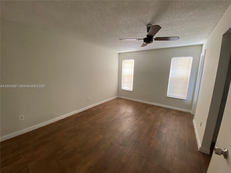 Interior space featuring wood-finish flooring, two dual-pane windows with fitted blinds, and a ceiling fan