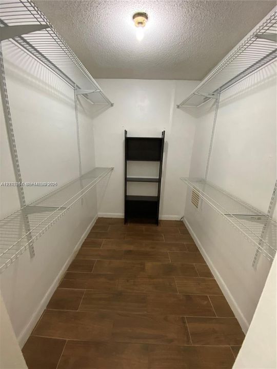 Walk-in closet featuring wood-finish tile flooring and multi-level white wire shelving