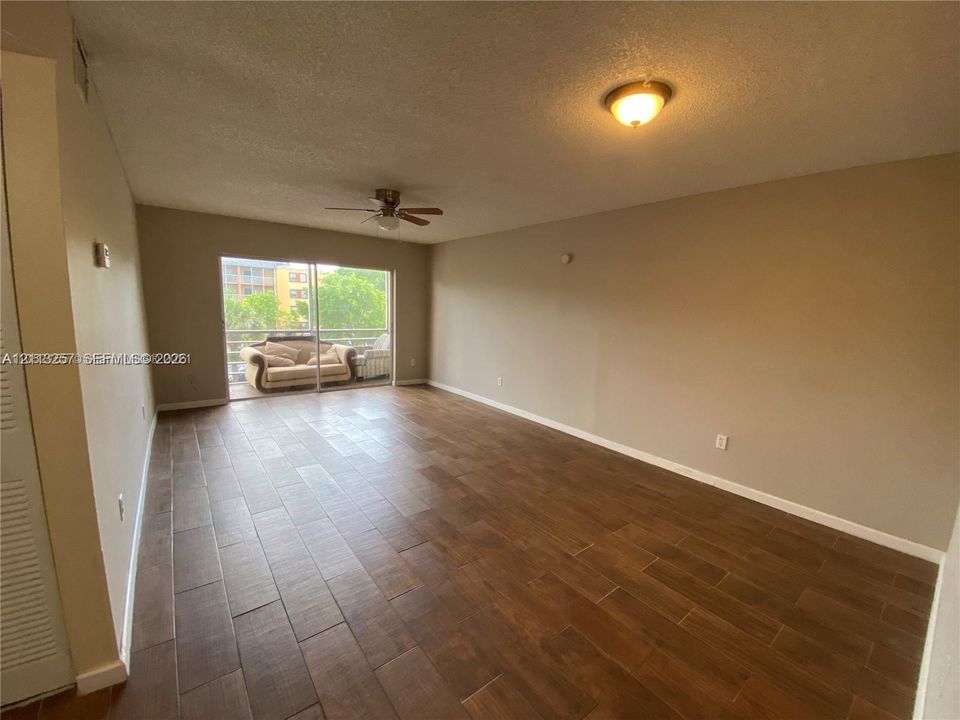 Spacious room featuring wood-finish flooring, a ceiling fan, and sliding glass doors