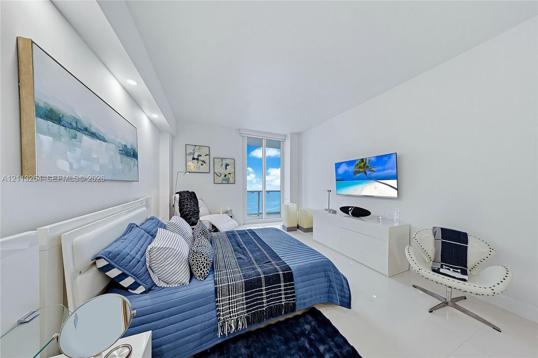 Spacious interior featuring high-gloss tile flooring, recessed ceiling lighting, and a glass-paneled door leading to an outdoor balcony