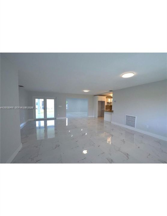 Large-format, polished stone flooring, recessed ceiling lighting, French doors, and a built-in kitchen peninsula