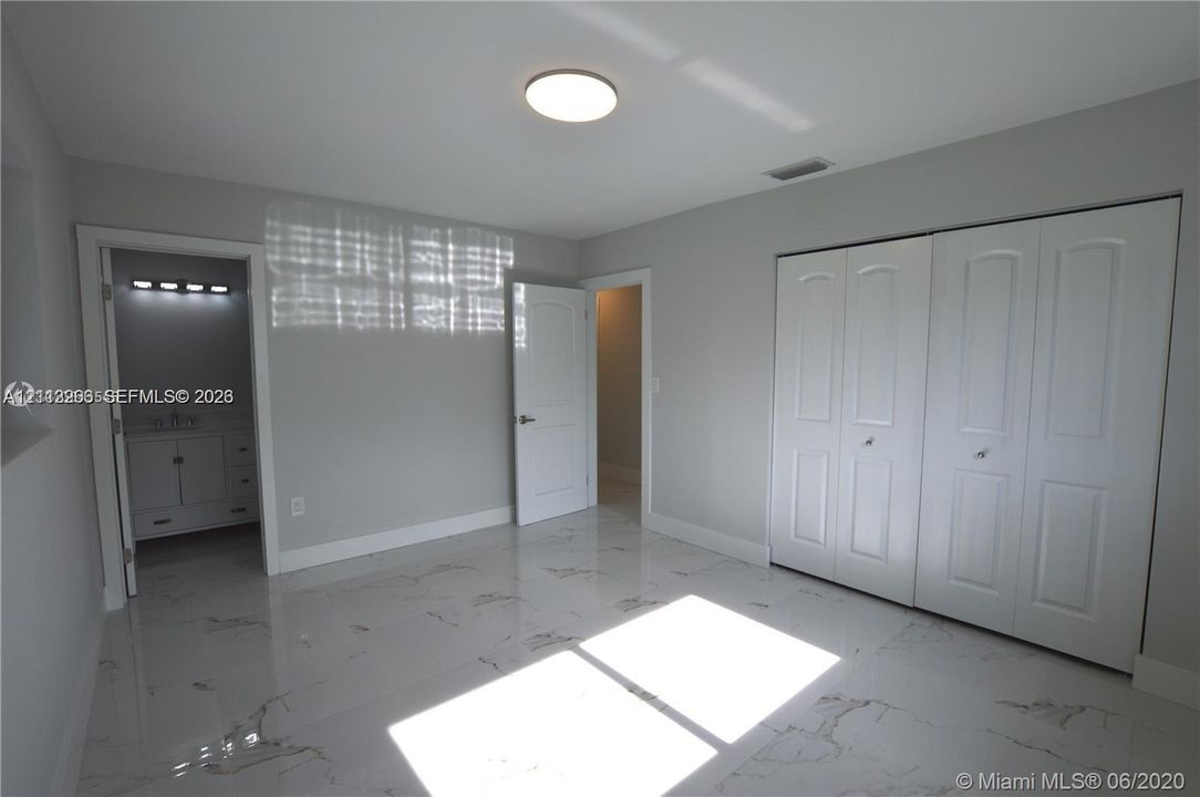 Interior space featuring polished stone-finish tile flooring, recessed ceiling lighting, and two-panel closet doors