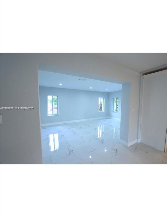 Interior space featuring light-toned flooring with decorative veining, recessed ceiling lighting, and multiple windows