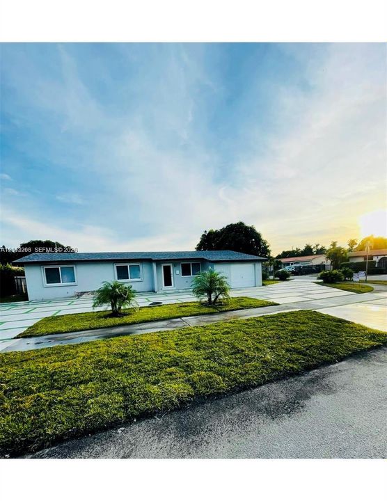 Single-story exterior featuring a paver driveway, manicured lawn, and attached garage