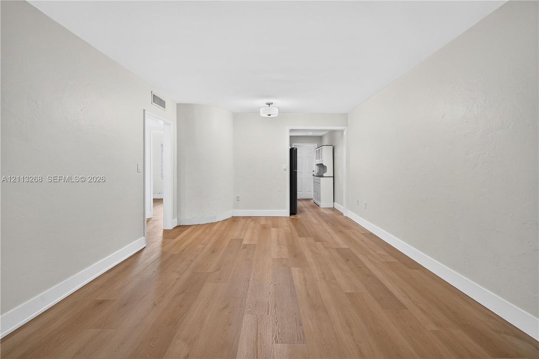 Neutral wall tones, wood-finish flooring, and recessed ceiling lighting, featuring a curved architectural wall detail and a built-in kitchen cabinet unit