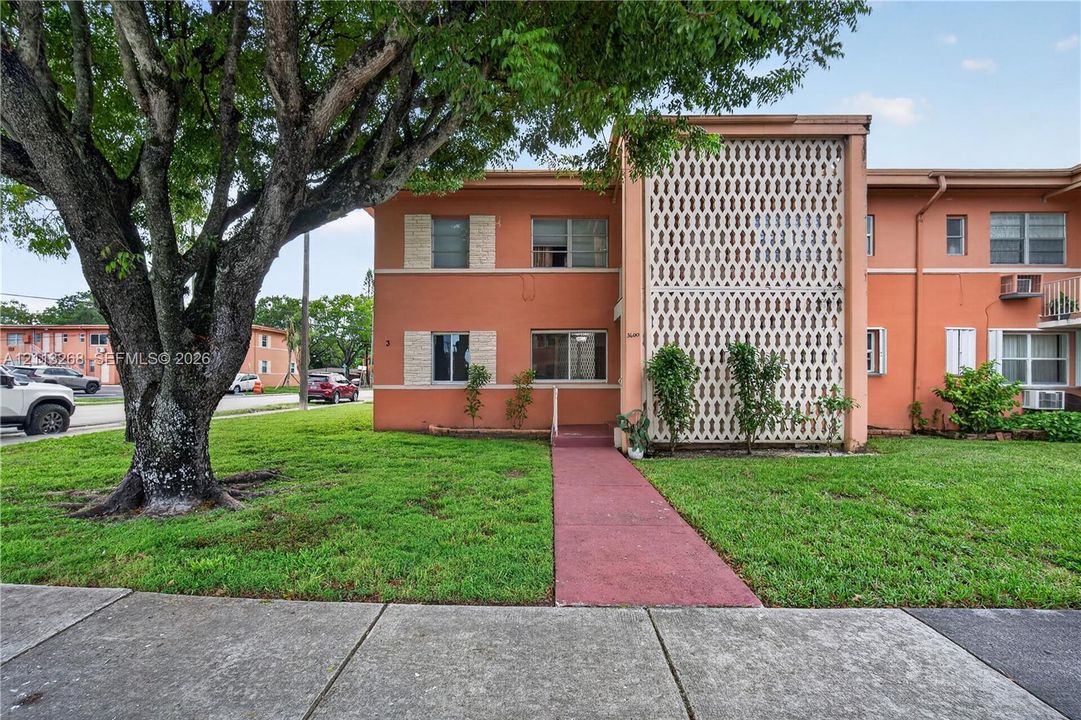 Multi-level exterior featuring stucco siding, decorative breeze block screening, horizontal windows, and a paved walkway