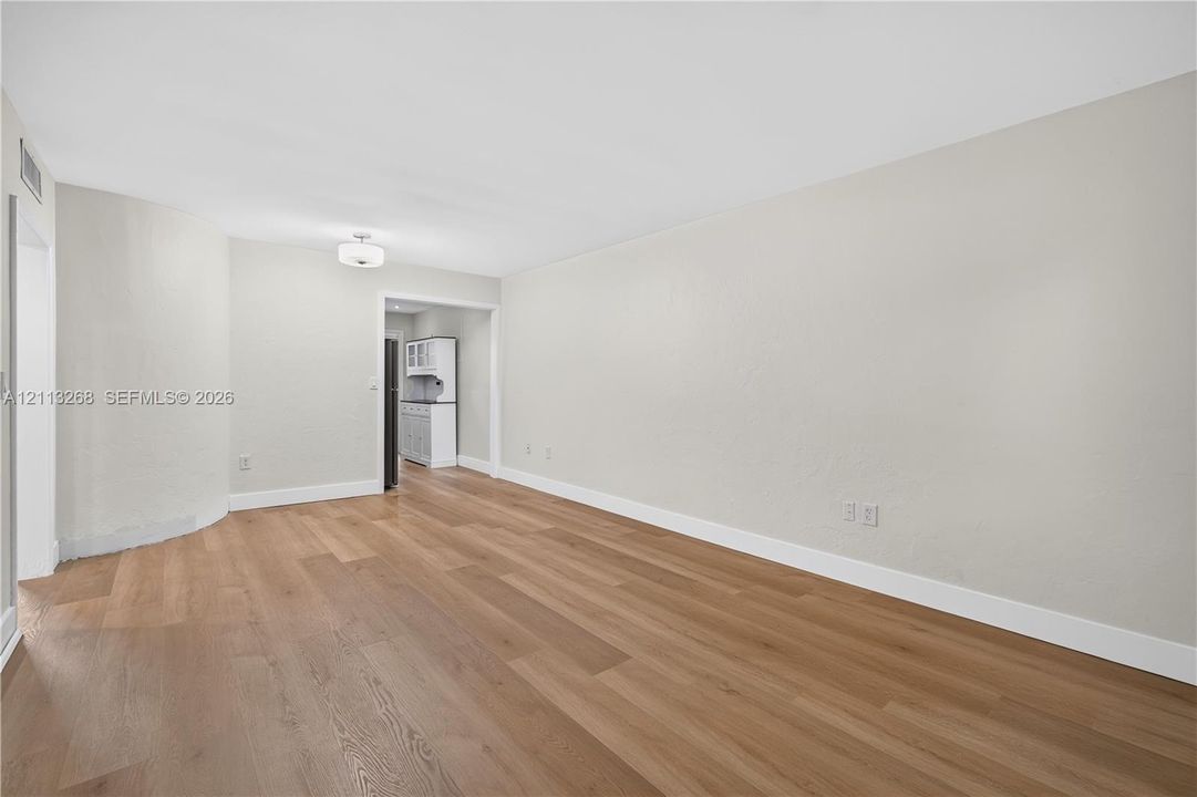 Neutral wall finishes, wood-finish flooring, and a flush-mount drum ceiling light fixture