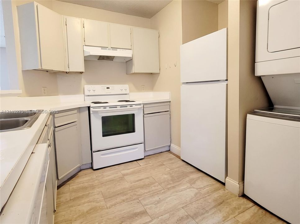Kitchen featuring neutral cabinetry, white appliances, a double-basin sink, and tile flooring, including an integrated laundry area