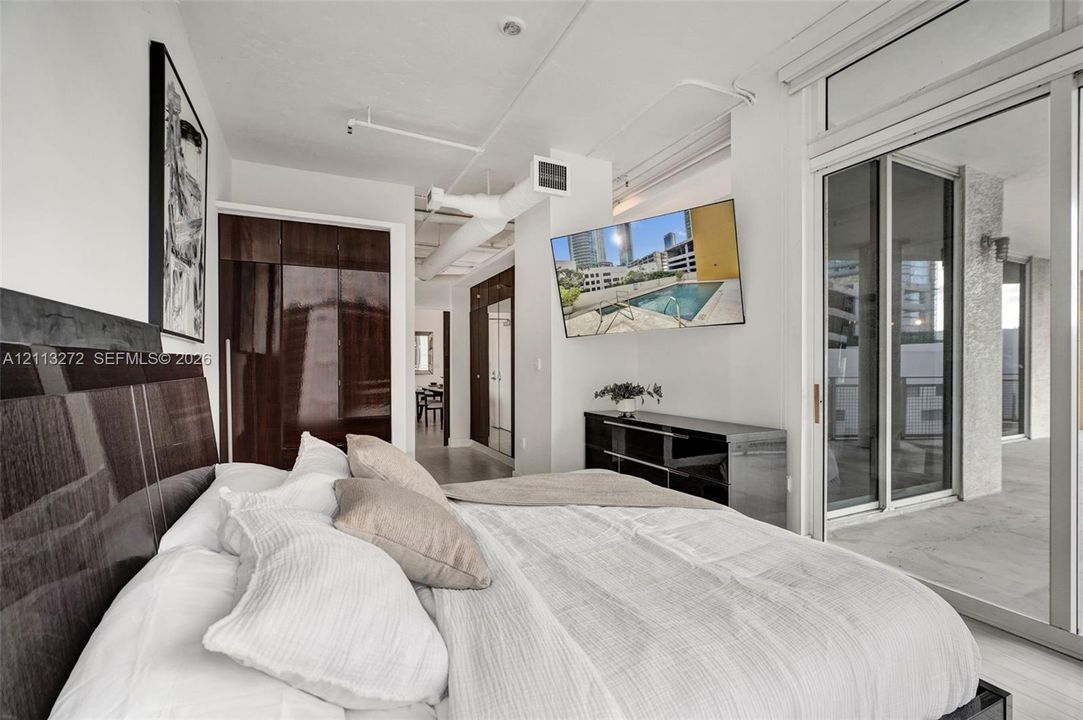 Industrial-style interior with exposed ceiling ductwork, dark wood-finish built-in cabinetry, sliding glass doors, and concrete-finish flooring