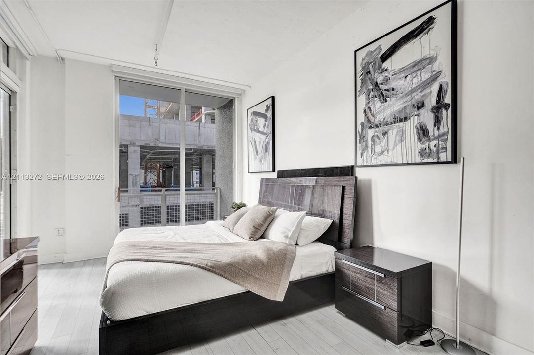 Expansive floor-to-ceiling glass sliding doors, neutral light-toned wood-finish flooring, and high ceilings