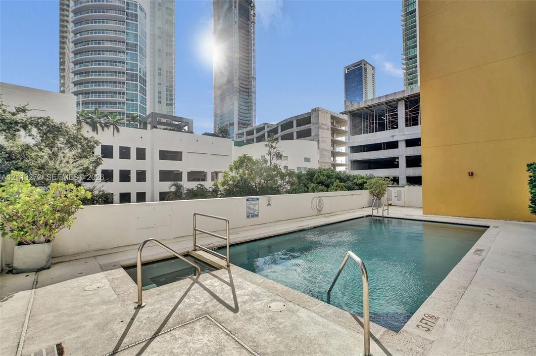 Swimming pool featuring a concrete deck, built-in metal handrails, and a dedicated wading area