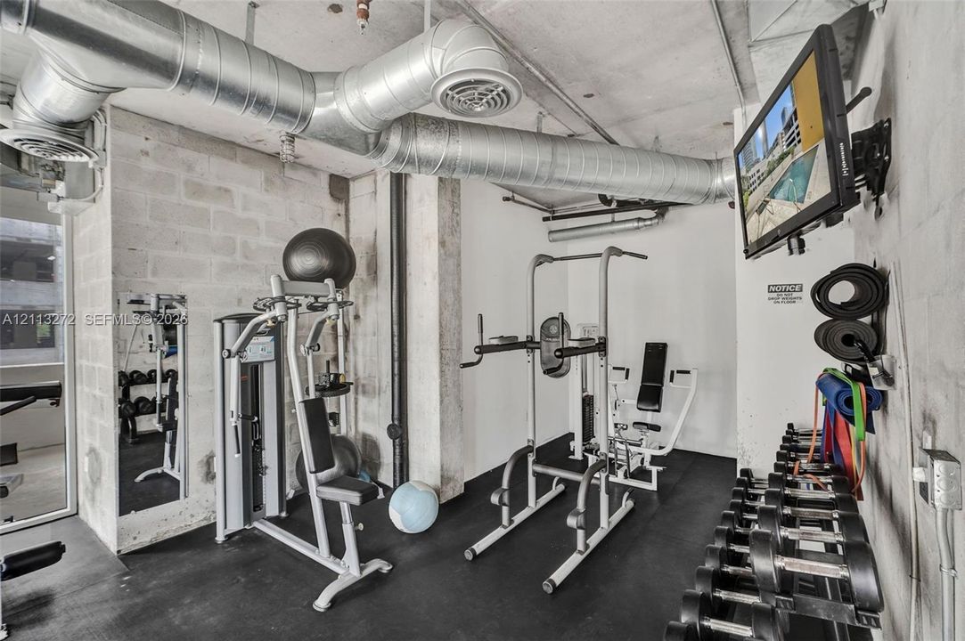 Industrial-style interior featuring exposed concrete masonry unit walls, exposed galvanized steel ductwork, and black rubberized flooring
