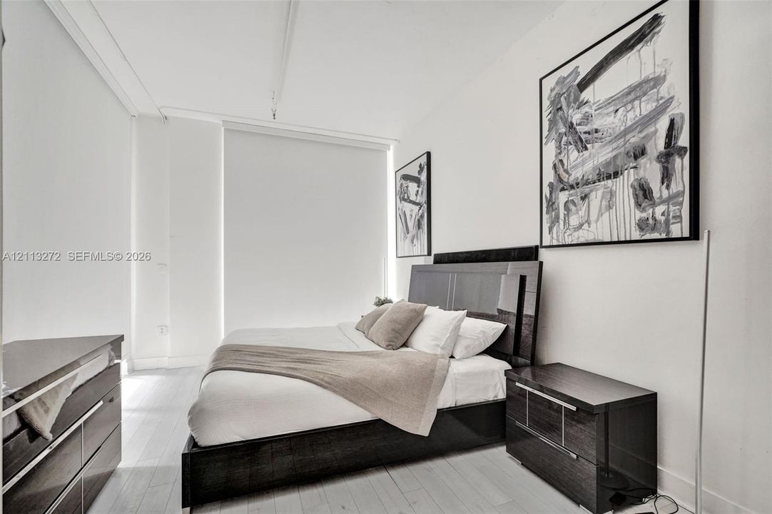 Light-toned wood-finish flooring and expansive floor-to-ceiling windows with roller shades
