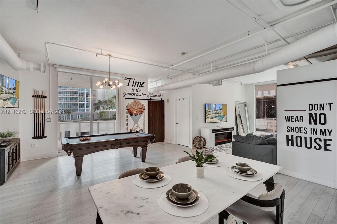 Open-concept living space featuring high ceilings with exposed ductwork, wood-finish flooring, floor-to-ceiling glass sliding doors, and a rustic sliding barn door