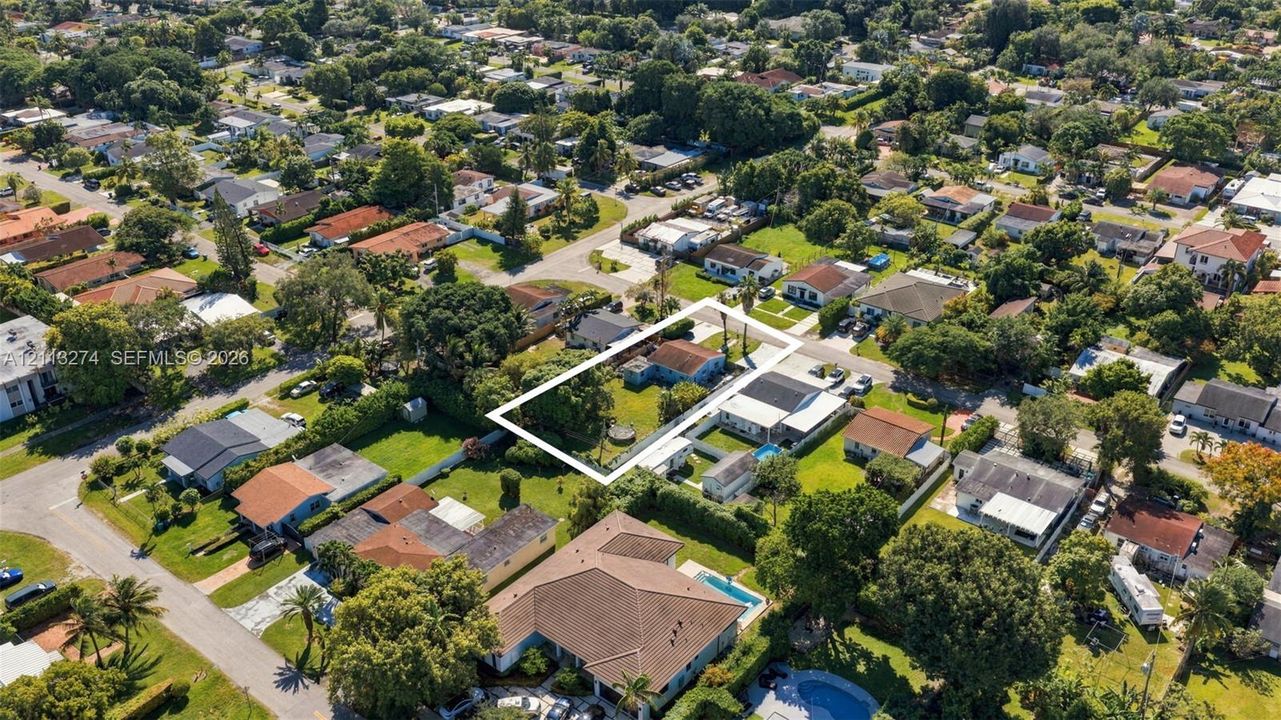 Aerial perspective featuring a rectangular lot, mature trees, and an established residential neighborhood
