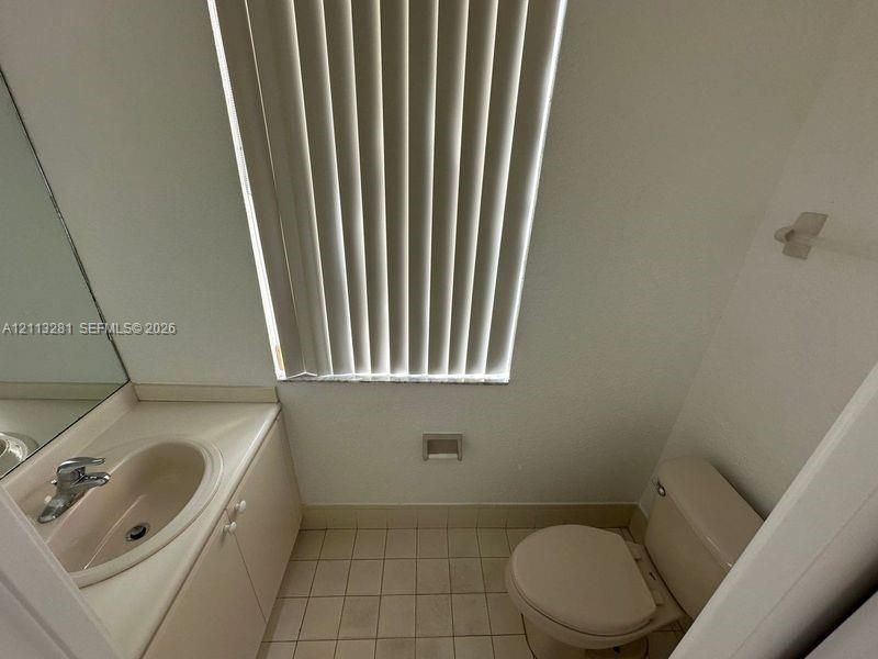 Bathroom featuring a vanity with an integrated sink, polished chrome faucet, tile flooring, and vertical window blinds