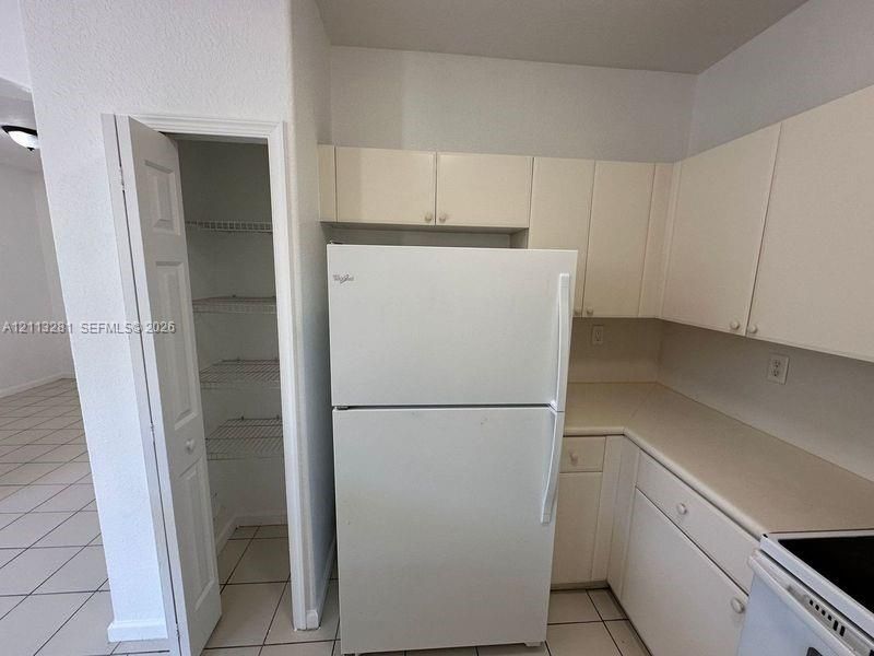 Kitchen area featuring white cabinetry, solid surface countertops, and an integrated pantry with wire shelving