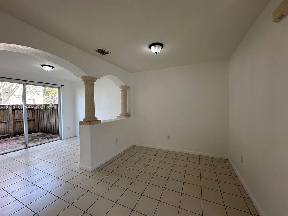Interior space featuring ceramic tile flooring, architectural archways with decorative pillars, and sliding glass doors