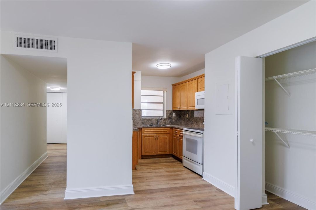 Kitchen featuring wood-finish cabinetry, stone-texture countertops, and an integrated white electric range with microwave