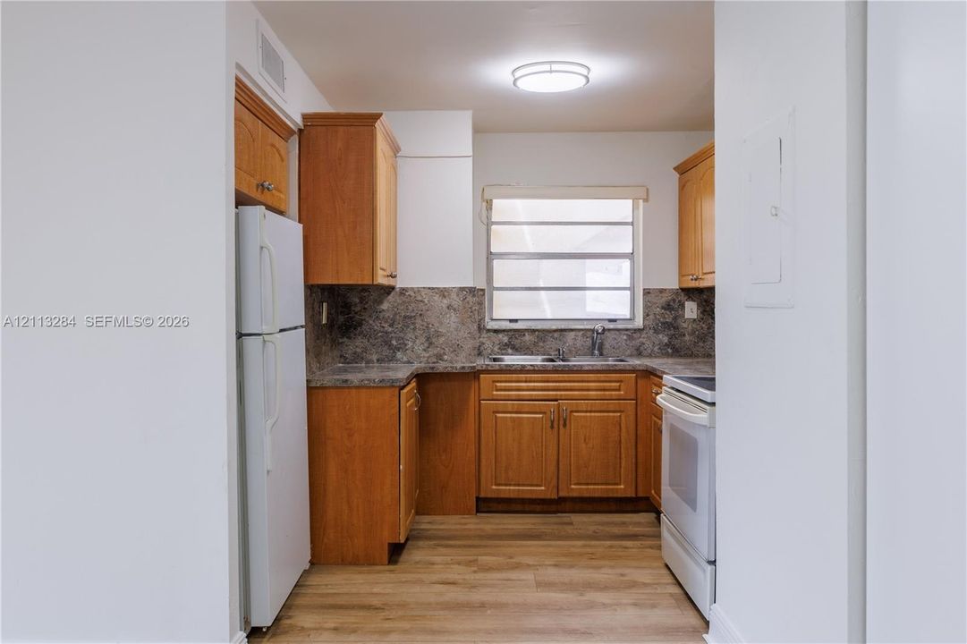 Kitchen featuring wood cabinetry, stone-finish countertops, tile backsplash, wood-finish flooring, and recessed ceiling lighting
