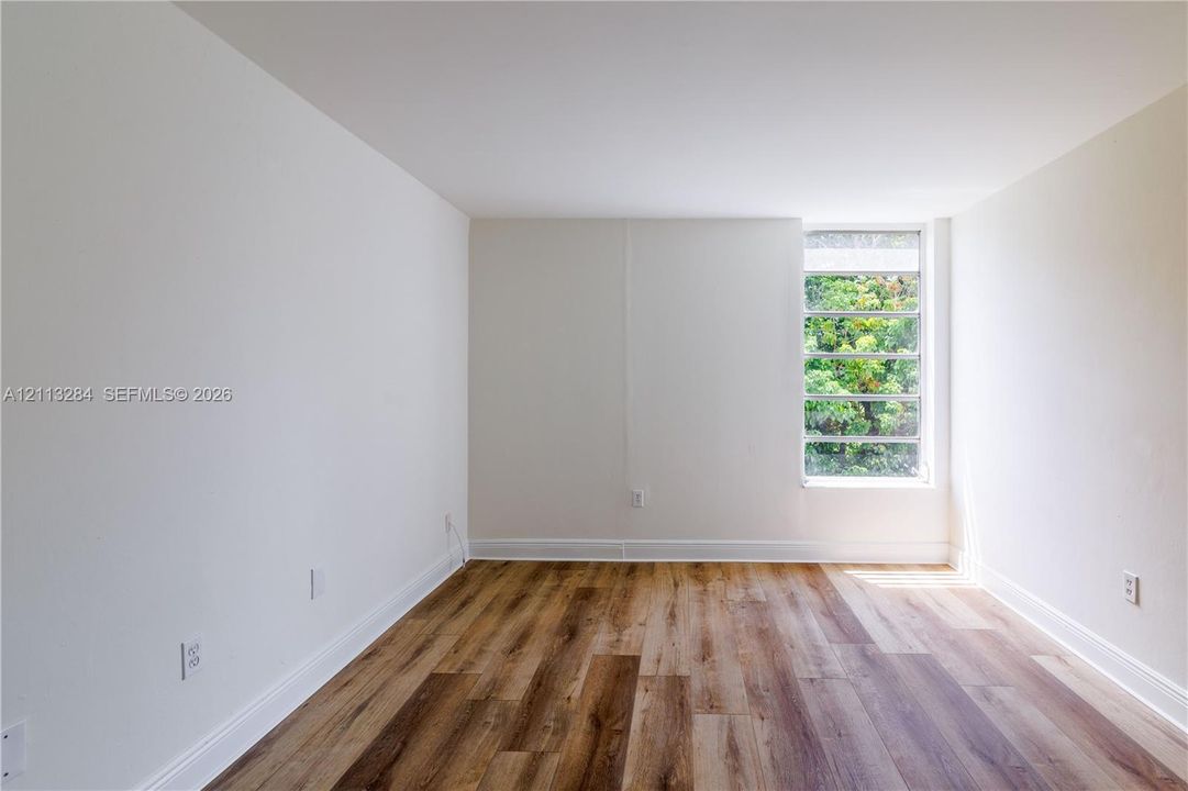 Neutral interior space featuring wood-finish flooring and a multi-pane window