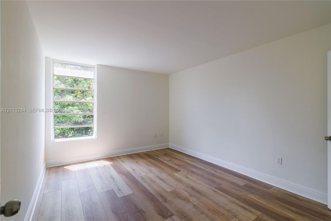 Neutral interior room featuring wood-finish flooring and a multi-pane horizontal window