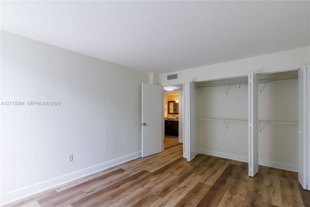 Wood-finish flooring, neutral wall tones, and a dual-panel closet with built-in shelving