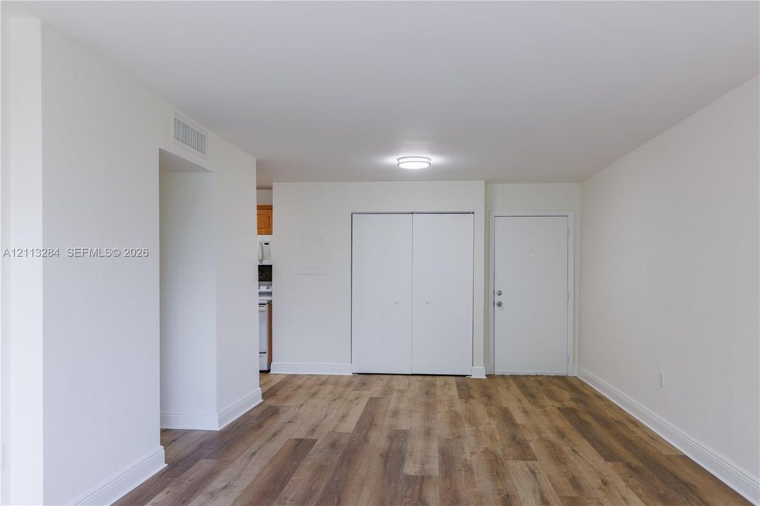 Neutral interior space featuring wood-finish flooring, white walls, flush-mount ceiling lighting, and double-door closet storage