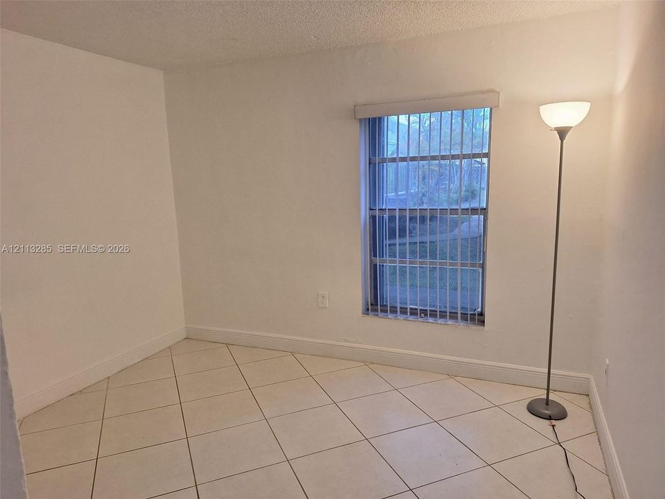 Neutral-toned ceramic tile flooring, vertical window blinds, and crisp white wall finishes
