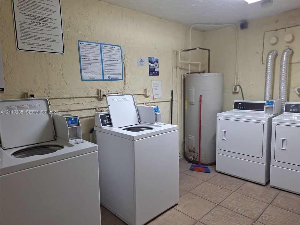 Laundry facility equipped with dual top-load washing machines, dual front-load dryers, and an integrated water heater