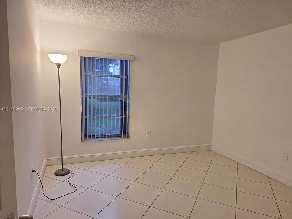 Interior room featuring neutral wall-to-wall ceramic tile flooring set on a diagonal pattern and a single window with vertical blinds