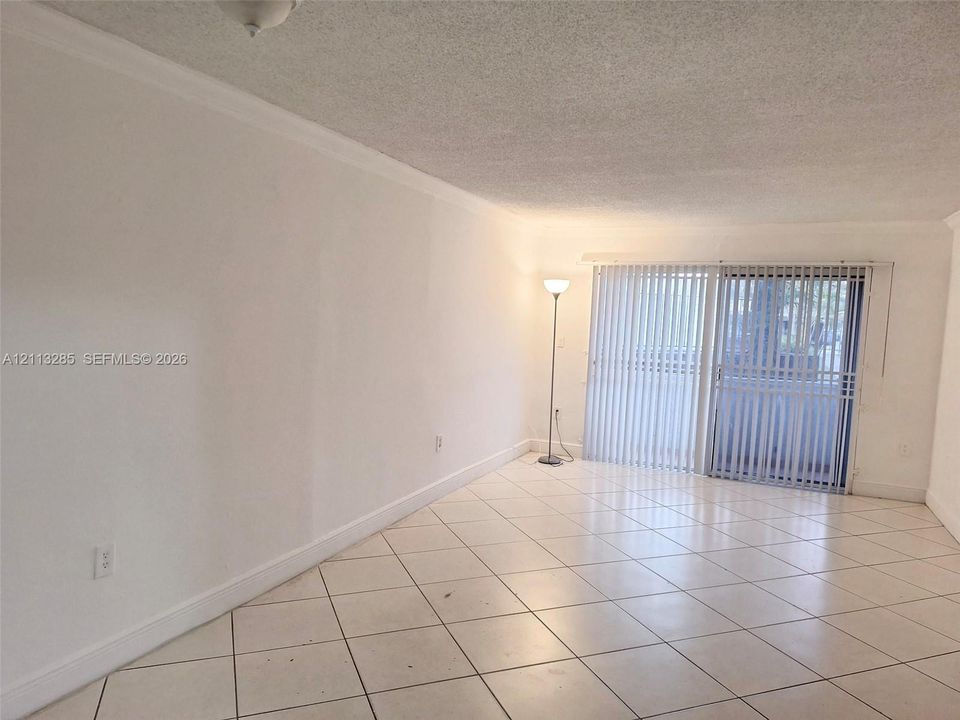 Interior space featuring large-format diagonal tile flooring, smooth wall finishes, and glass sliding doors with vertical blinds