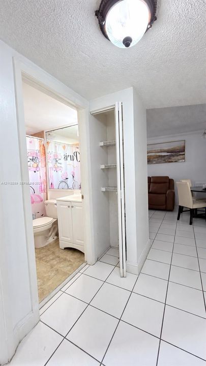 Ceramic tile flooring, built-in recessed shelving, wall-mounted flush-mount lighting, and white cabinetry