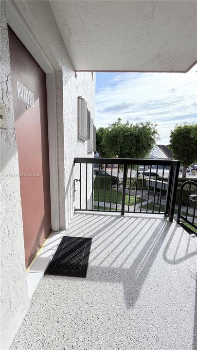 Covered exterior landing with textured finish, metal railing, and direct entry door
