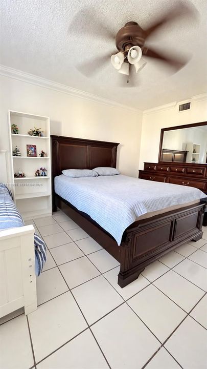 White tile flooring, built-in shelving unit, and a ceiling fan with integrated light fixture