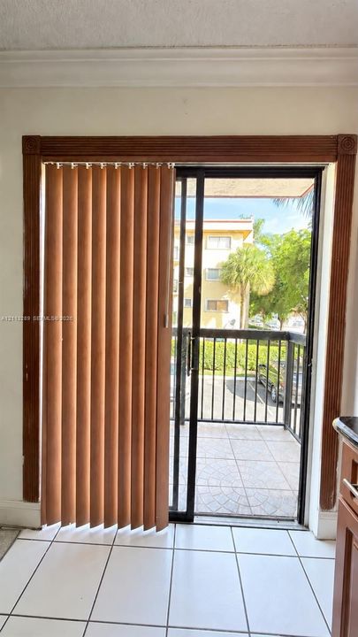 Sliding glass door featuring a black metal frame, ornate wooden molding surround, and ceramic tile flooring