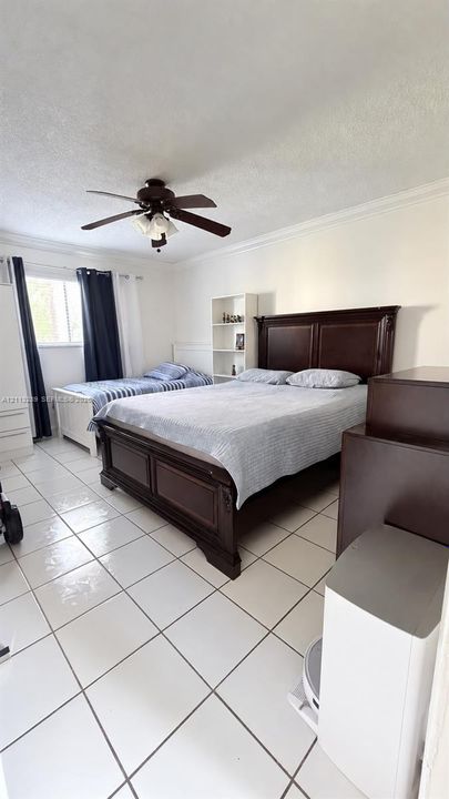 Room featuring tile flooring, ceiling fan with integrated lighting, and crown molding