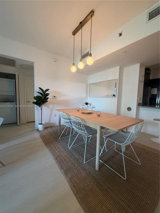 Multi-pendant linear light fixture with exposed bulbs, neutral wood-finish flooring, and wall-mounted mirror