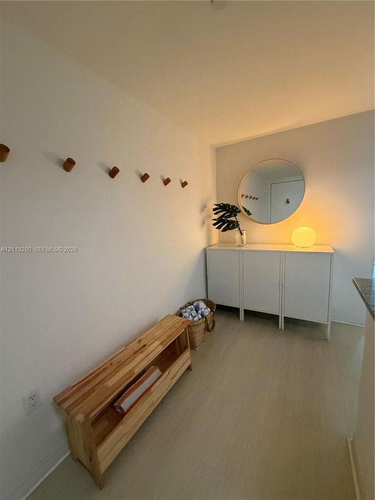 Wall-mounted wood peg hooks, circular wall mirror, and wood-finish flooring