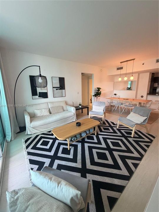 Open-concept interior featuring wood-finish flooring, recessed lighting, and a linear three-pendant light fixture over the dining area
