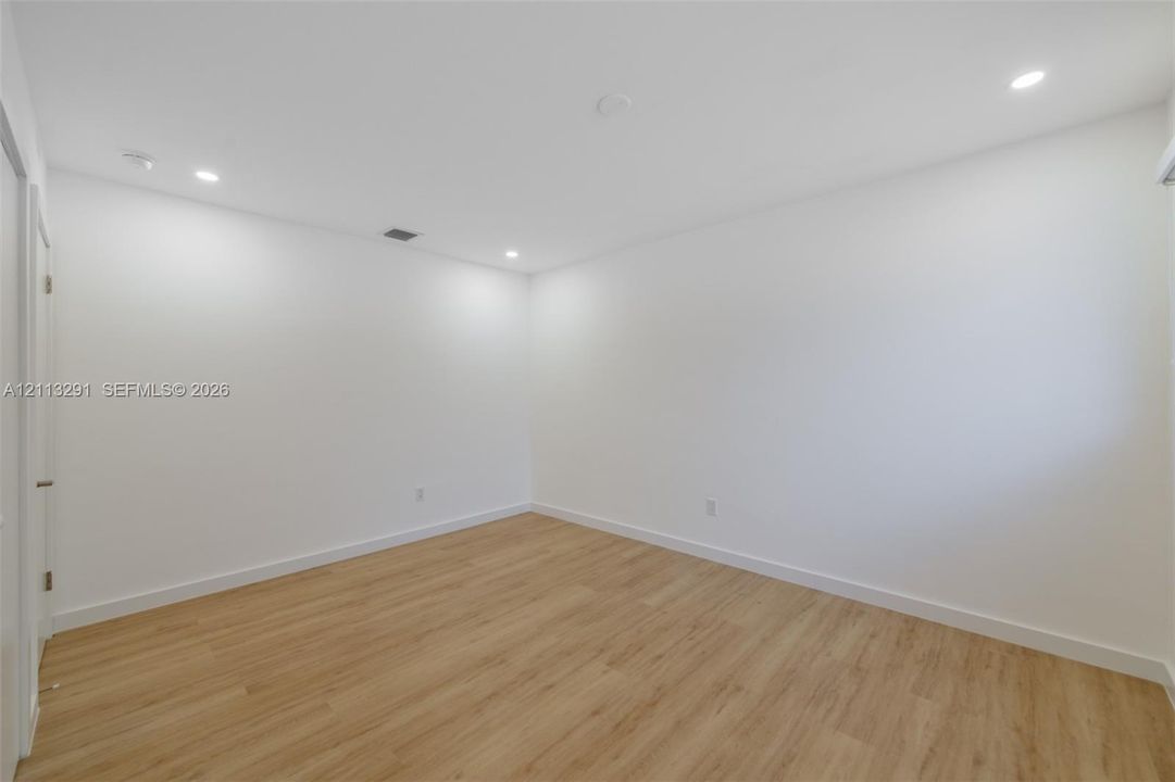 Neutral-toned interior space featuring wood-finish flooring, white walls, and recessed ceiling lighting